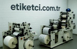etiket üretim firması ve etiket makinelerinin yer aldığı duvarda etiketci.com.tr yazan bir görsel
