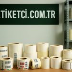 Rulo etiketçi üretim alanında masa üzerinde rulo etiket ve arka planda etiketci.com.tr tabelası bulunan depo görüntüsü